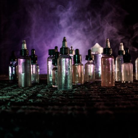 Vape,Concept.,Smoke,Clouds,And,Vape,Liquid,Bottles,On,Dark