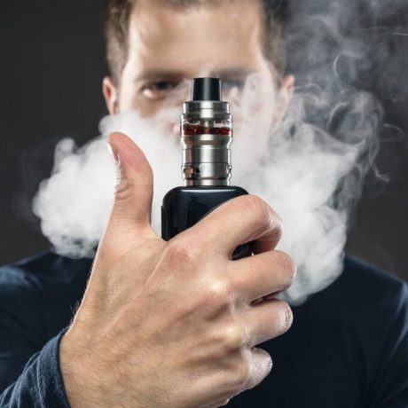 homme vapotant à la cigarette électronique à moitié caché par la fumée